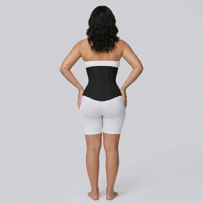 Person wearing a black waist trainer and white shorts on a gray background